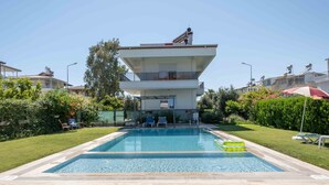 A modern two-story building with a swimming pool in the foreground. - Villa Belinda (Serik)