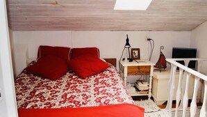 Een slaapkamer met een bed, bureau, stoel, televisie en raam.