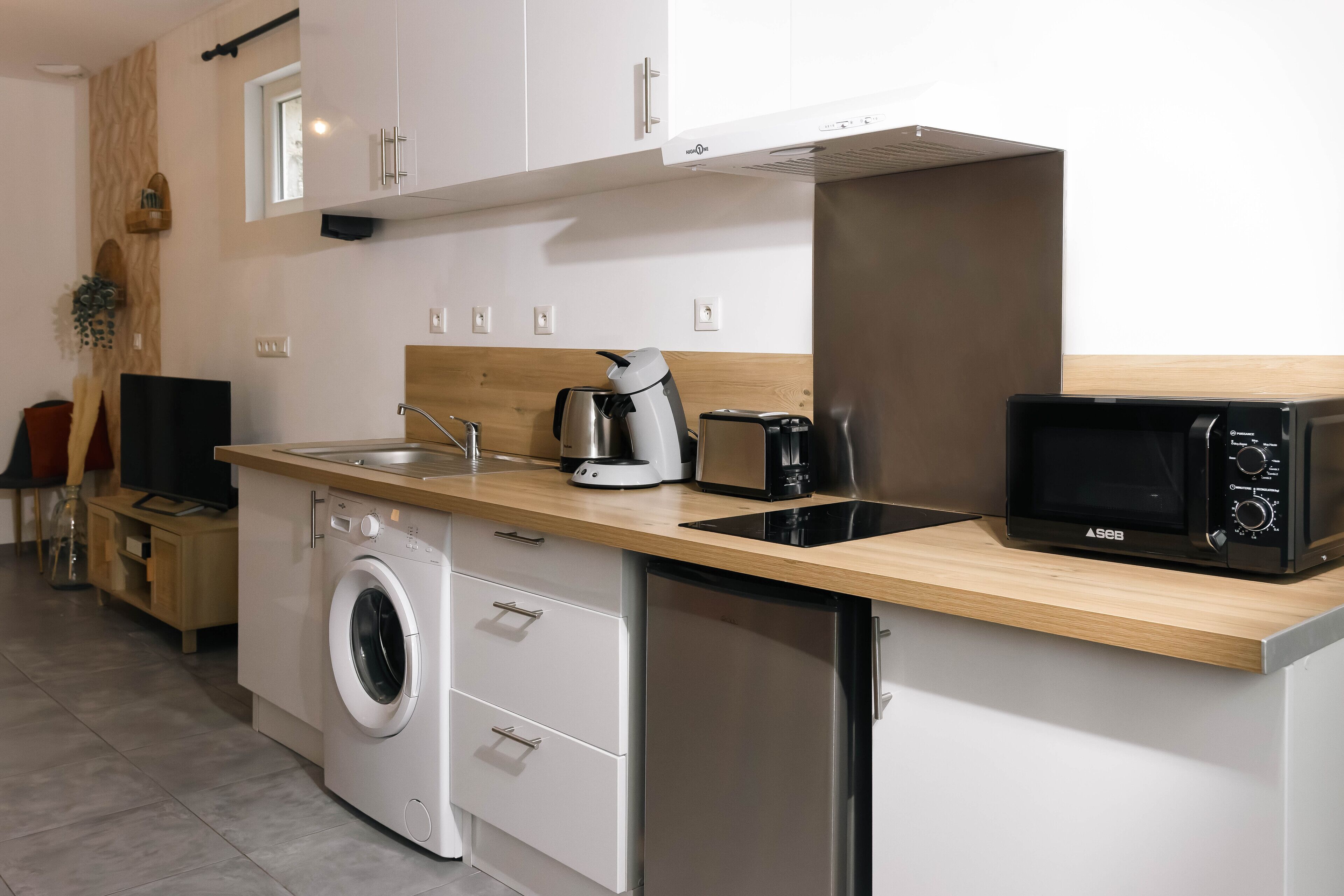 Een moderne keuken met een wasmachine, vaatwasser, magnetron en koffiezetapparaat.