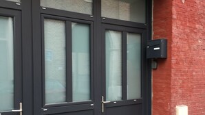 A black double door with a glass panel, a mailbox, and a brick wall. - T1 Idéalement Situé Hyper Centre/canal Plus (amiens)