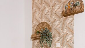 A corner with a chair, a vase with pampas grass, and a wall with a leaf pattern. - T1 Idéalement Situé Hyper Centre/canal Plus (amiens)