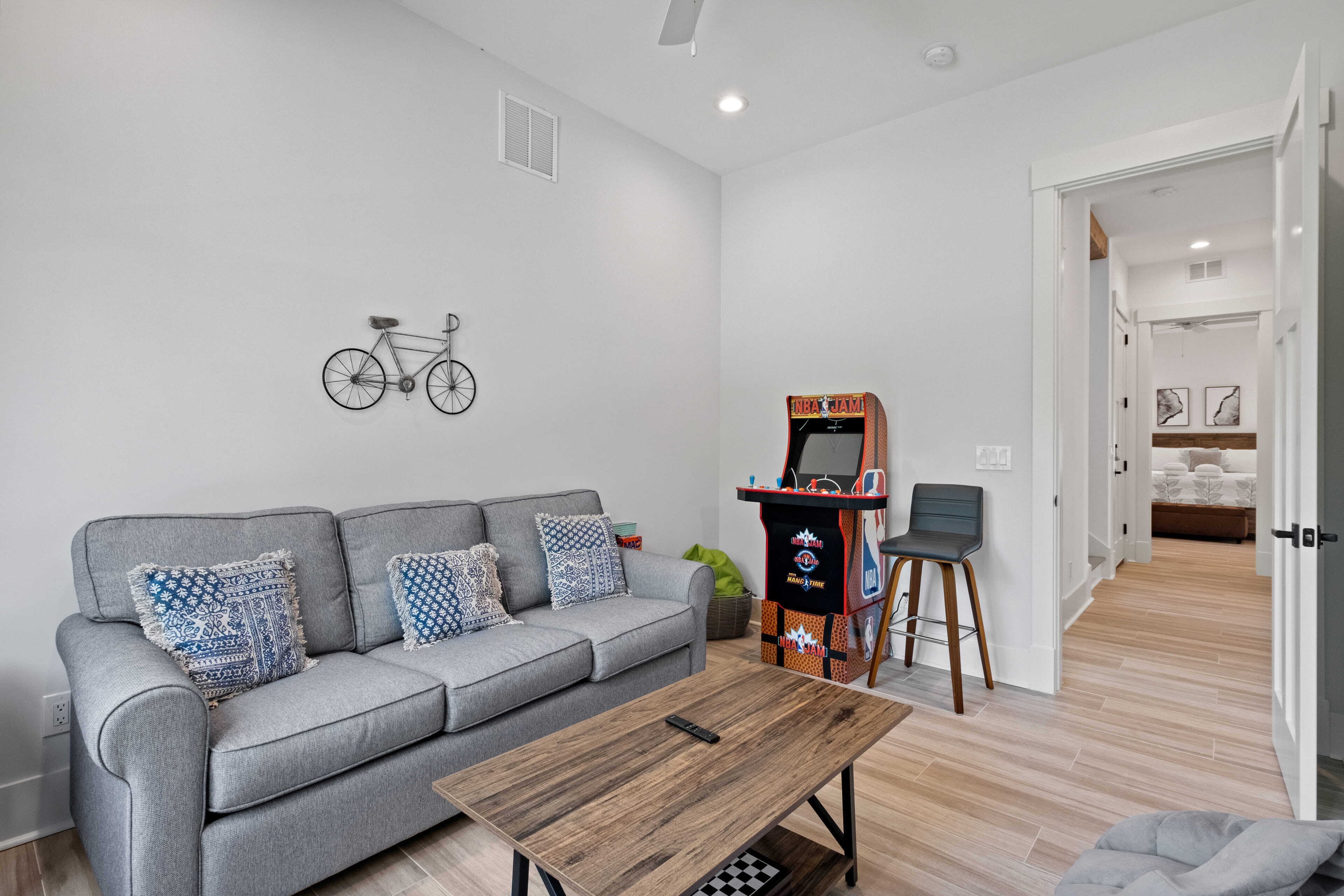 A modern living room with a grey sofa, a wooden coffee table, and a retro arcade machine.