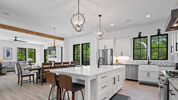 Una cocina moderna con armarios blancos, una isla grande e iluminación colgante.