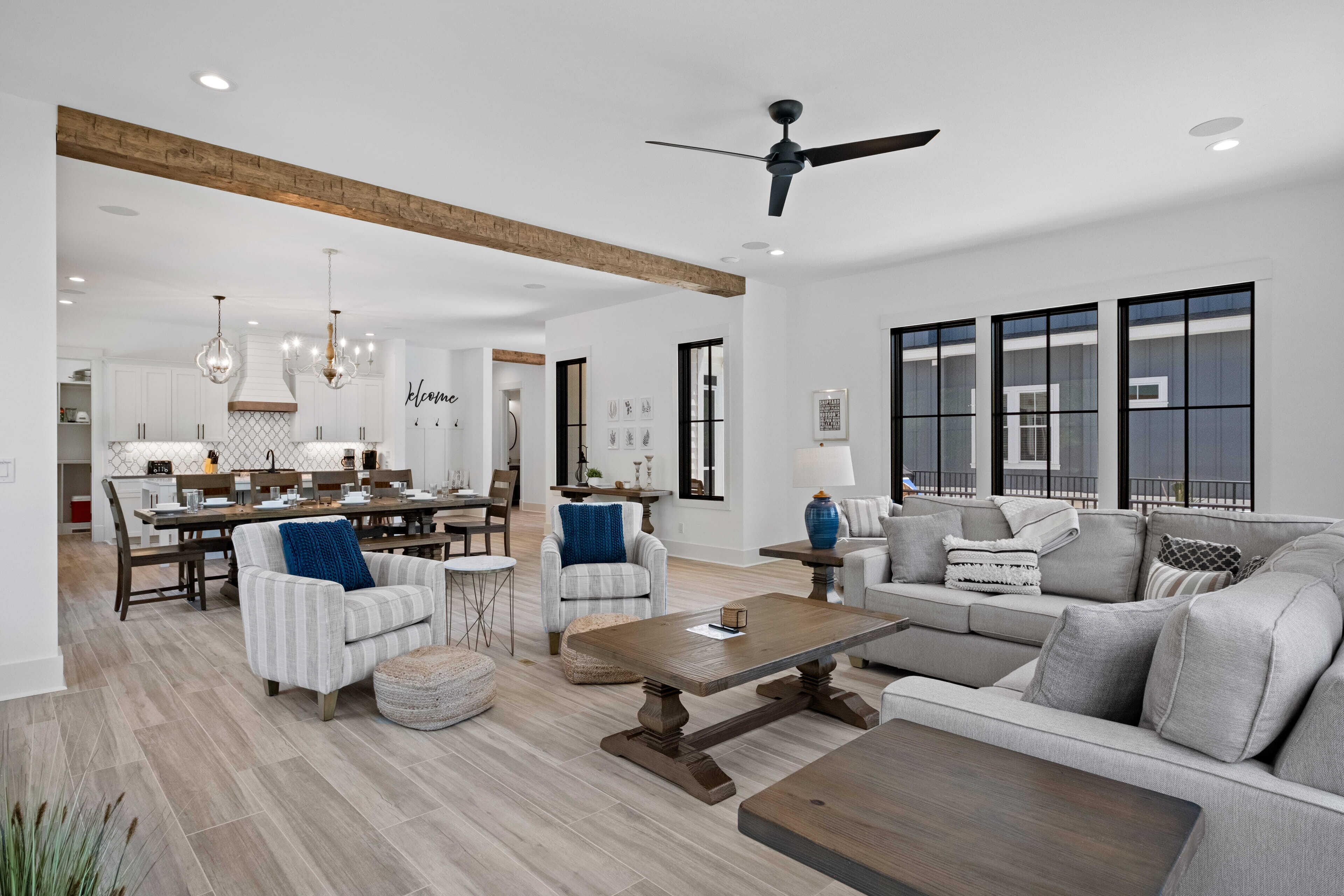 A spacious living room with a large sofa, a coffee table, and a dining area with a wooden table and chairs.