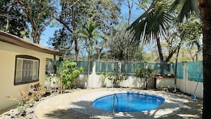 A swimming pool surrounded by a stone patio, a fence, and lush greenery. - Costa Rica Private Home with Swimming Pool . (Playa Hermosa)