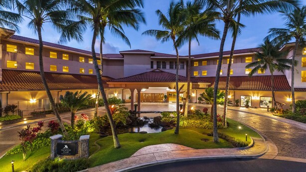Un hotel con piscina, palme e un cartello del Harleton Vacation Club.