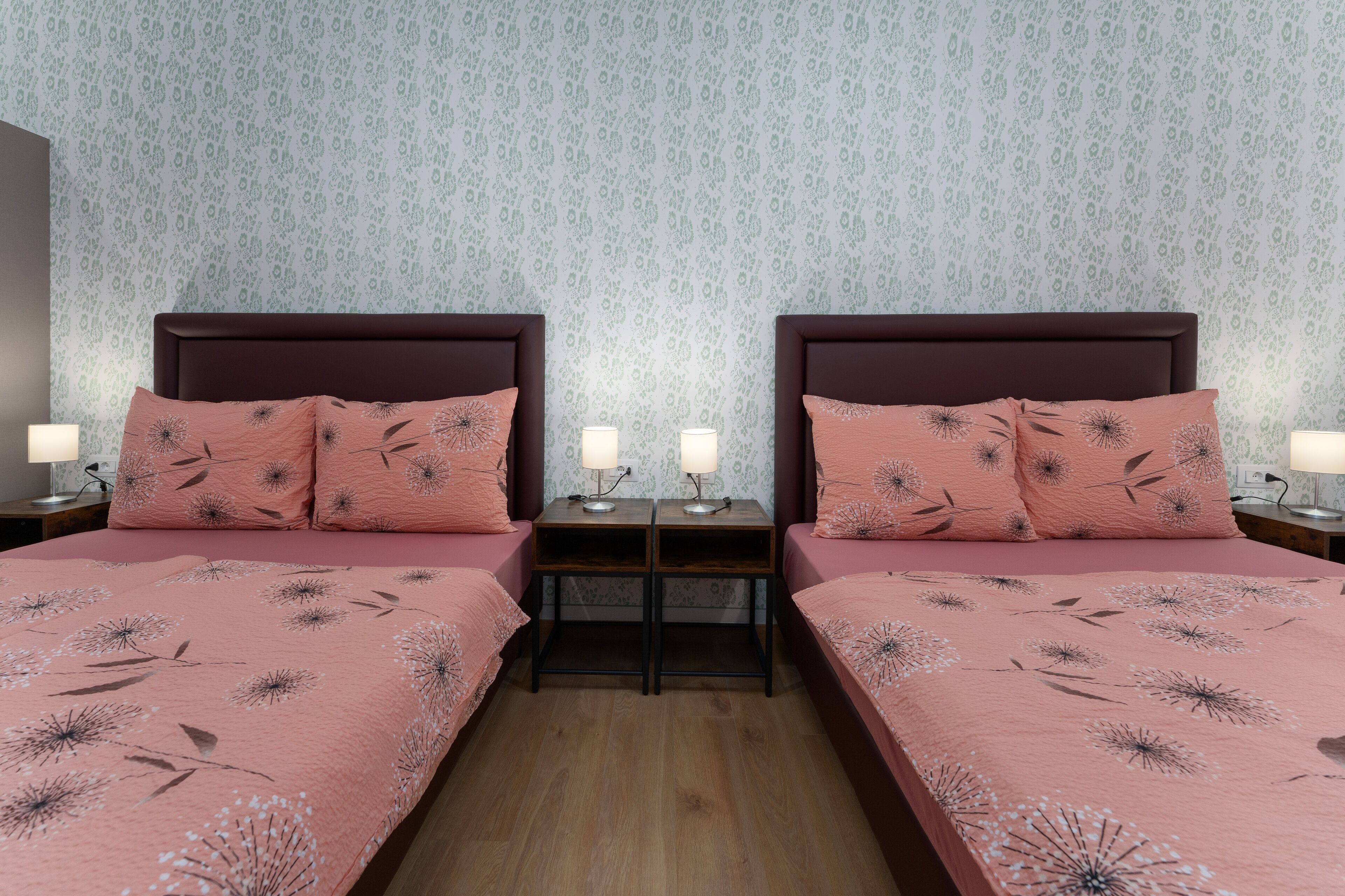 A double room with two beds, each with a headboard, and bedside tables with lamps.