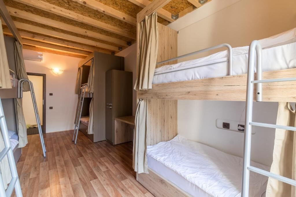 Habitación con literas, suelo de madera, un armario y una escalera.