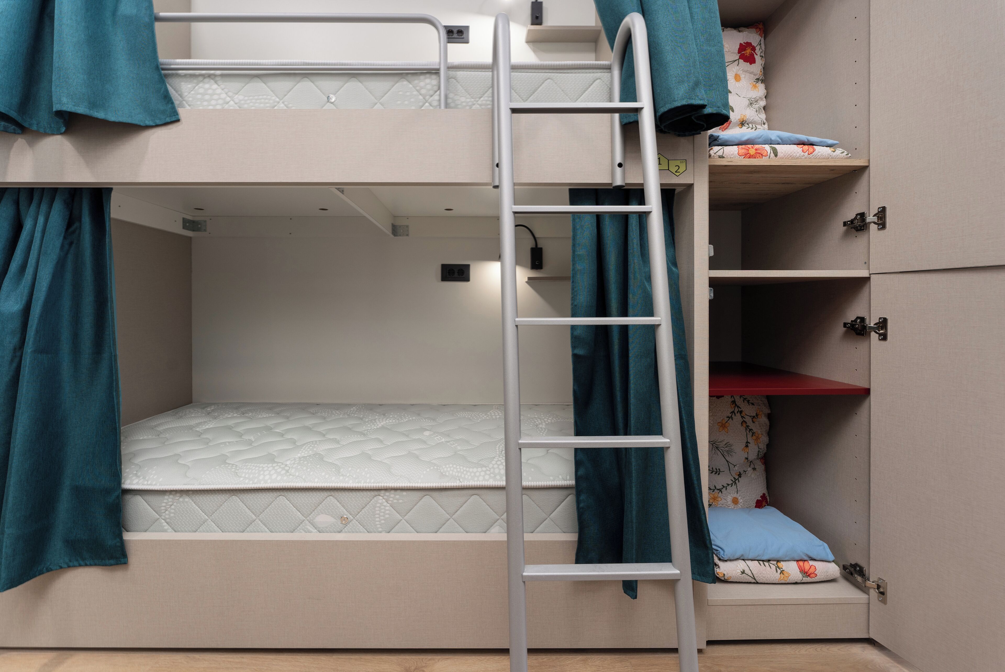 Un letto a castello con una scala, un letto inferiore e un armadio con ripiano rosso.