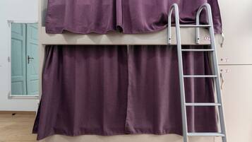 A bunk bed with purple bedding and a metal ladder.