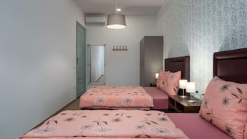 Une chambre avec deux lits, une table de chevet, un miroir et un luminaire fixé au mur.