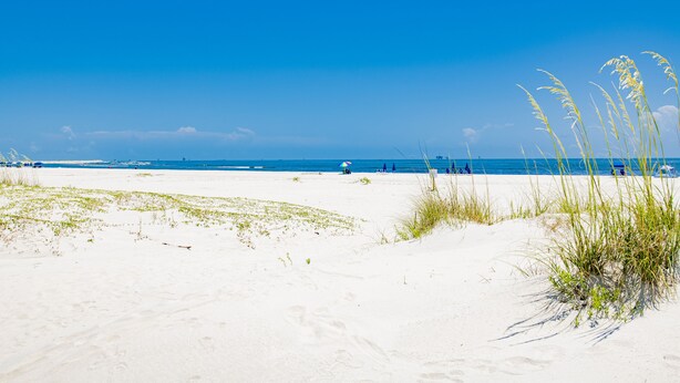 A beach with white sand, clear blue sky, and distant ocean. - SunTime at the BEACH! Updated 2nd Floor Unit! GREAT Views of 2 Pools and Gulf! (Dauphin Island)