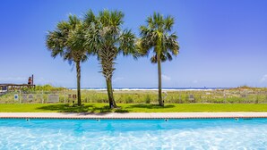 A swimming pool with clear blue water, surrounded by a white fence and palm trees. - SunTime at the BEACH! Updated 2nd Floor Unit! GREAT Views of 2 Pools and Gulf! (Dauphin Island)