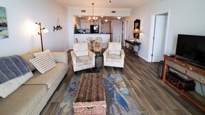 A living room with a sofa, two armchairs, a coffee table, a television, and a ceiling fan. - SunTime at the BEACH! Updated 2nd Floor Unit! GREAT Views of 2 Pools and Gulf! (Dauphin Island)