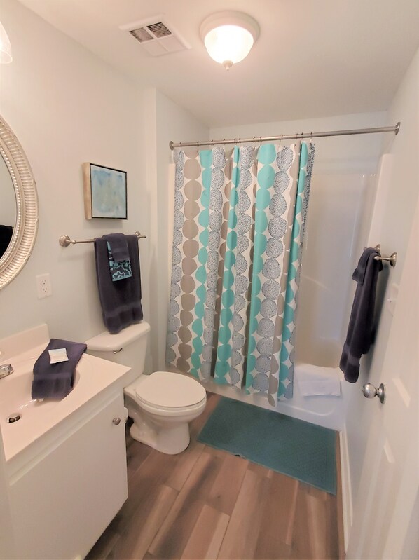 Un baño con inodoro, lavamanos y cortina de ducha.
