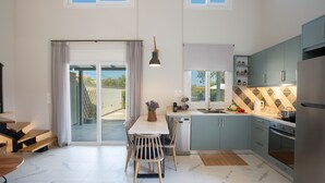 A modern kitchen with a dining area, large windows, and a sliding glass door leading to a balcony. - Vertzami Villa just 2km from Lefkada city center (Lefkada)