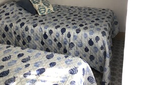 Quarto com duas camas, uma obra de arte de peixes na parede e um objeto decorativo na parede.