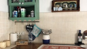 Cozinha com armários verdes, bancada de madeira e luminária pendente.
