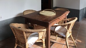 Uma sala de jantar com mesa de madeira e cadeiras de vime, piso ladrilhado e decoração na parede.