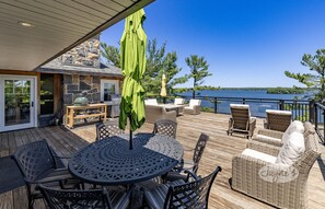 A deck with outdoor furniture, a grill, and a view of the lake. - Incredible 9 bdrm, 9 bath, Tennis Court! Nanny Suite! Gym! Lake Muskoka!!! (Port Carling)