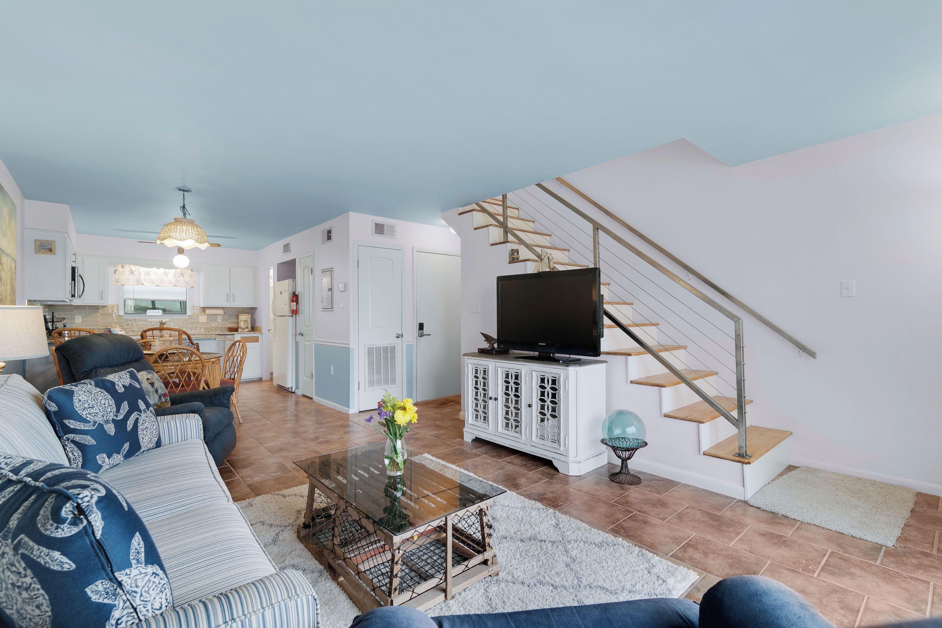 Un salon moderne avec un canapé, une table basse, un téléviseur et un escalier.