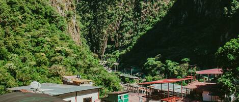 A mountainous landscape with a small settlement featuring buildings with corrugated metal roofs and a few brick structures.