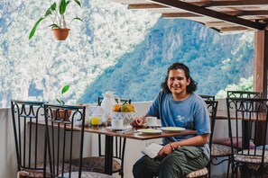 A person seated at a table with a view of a mountainous landscape.