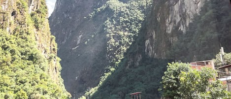 Vista a través de una ventana de un paisaje montañoso con riscos escarpados y vegetación densa.