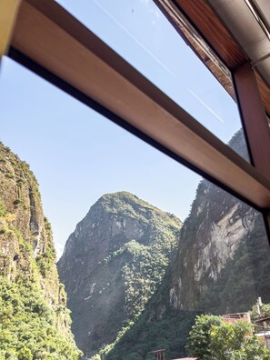 A view through a window of a mountainous landscape with steep cliffs and dense greenery.
