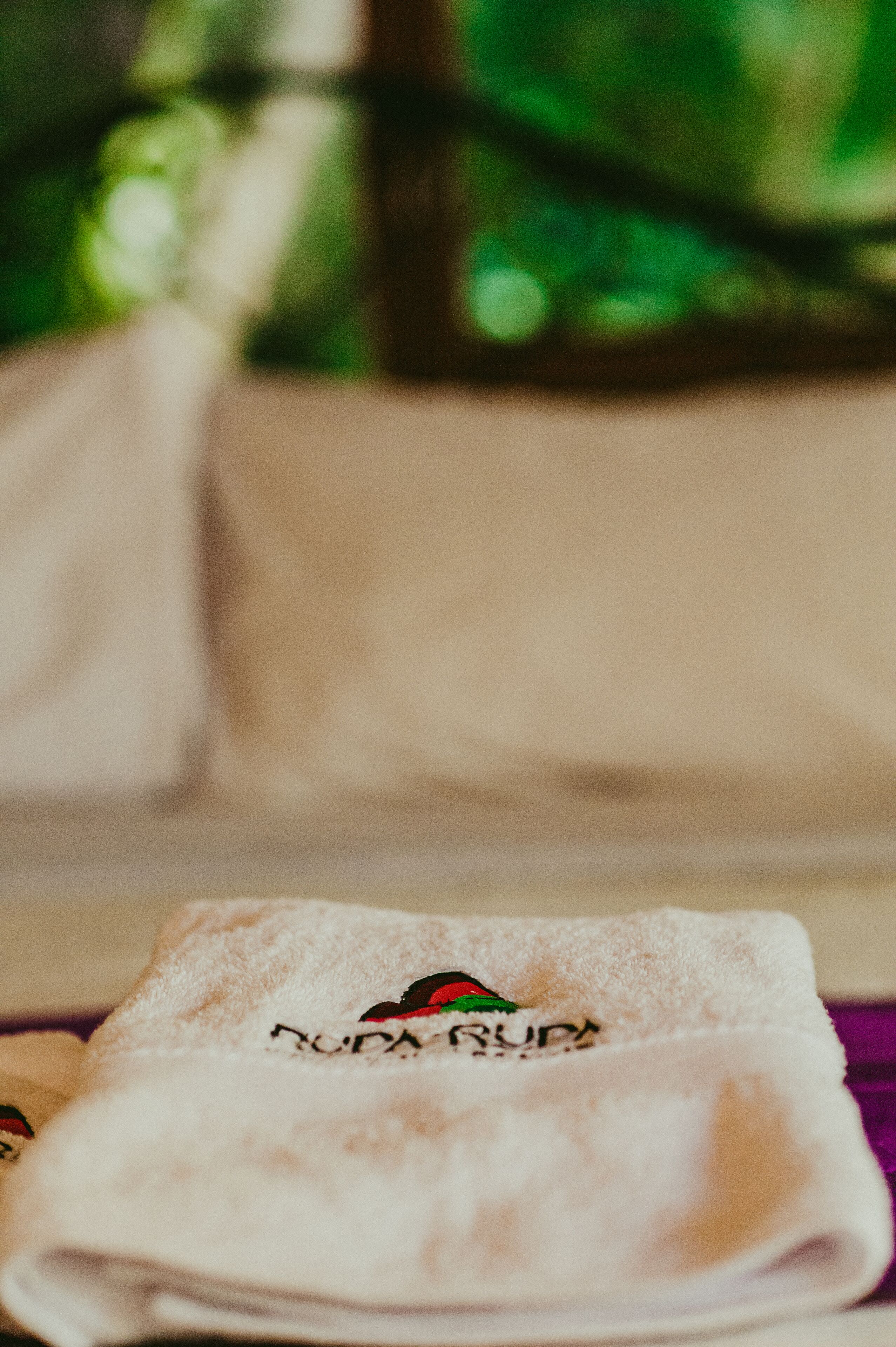 A neatly folded towel with a logo and text, placed on a surface with a blurred background.