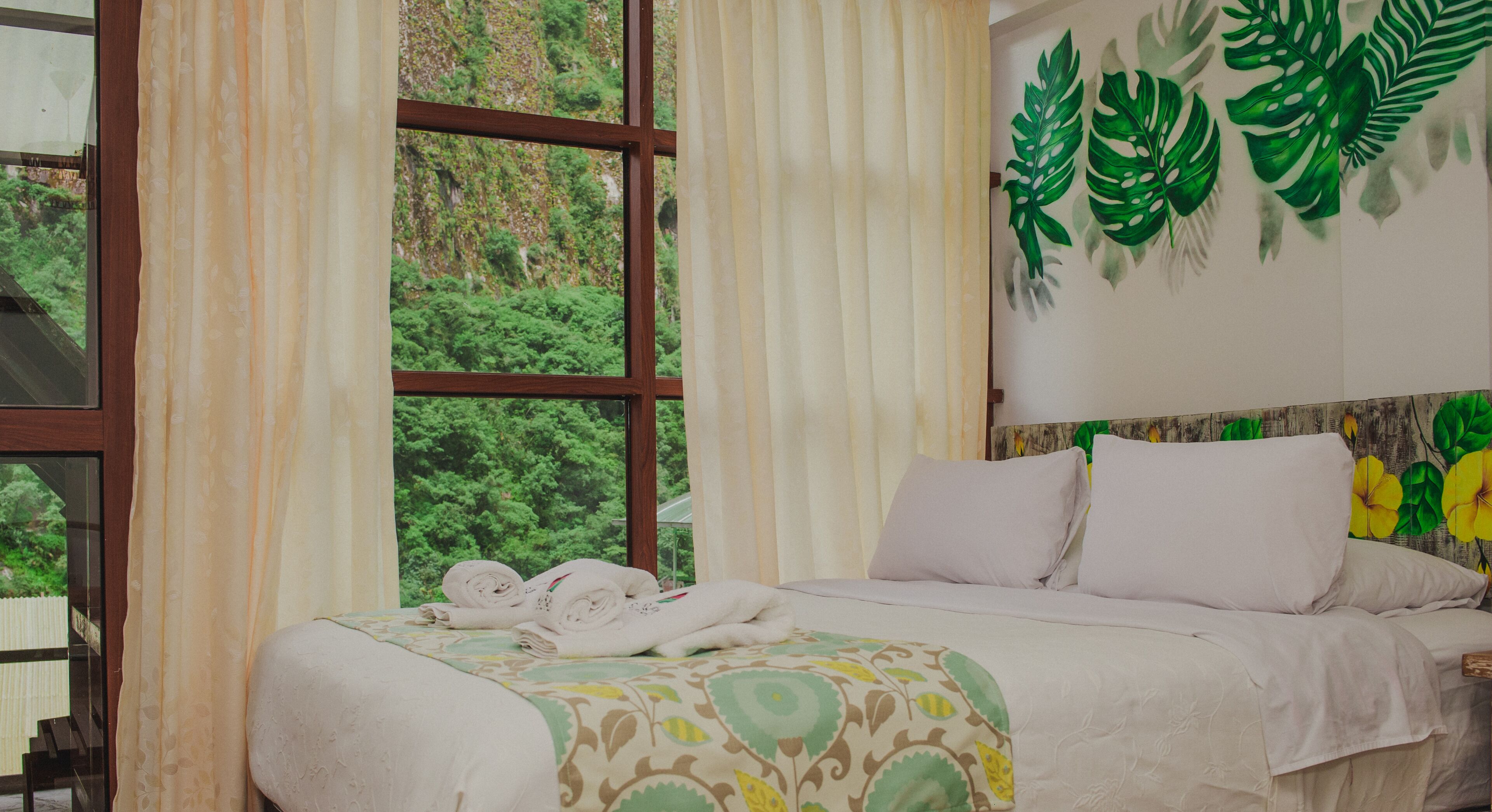 Habitación de hotel con cama, cortinas y ventana con vista a follaje.