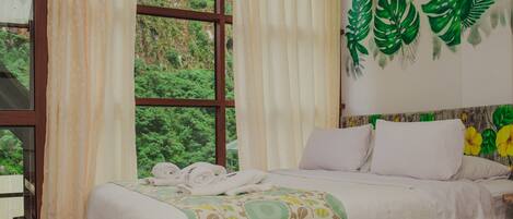 Habitación de hotel con cama, cortinas y ventana con vista a follaje.