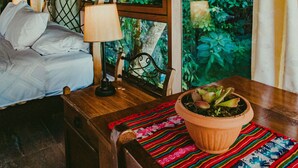 A room with a bed, a table with a potted plant, and a window with curtains. - Rupa Rupa High Jungle Eco B&B (Machu Picchu)