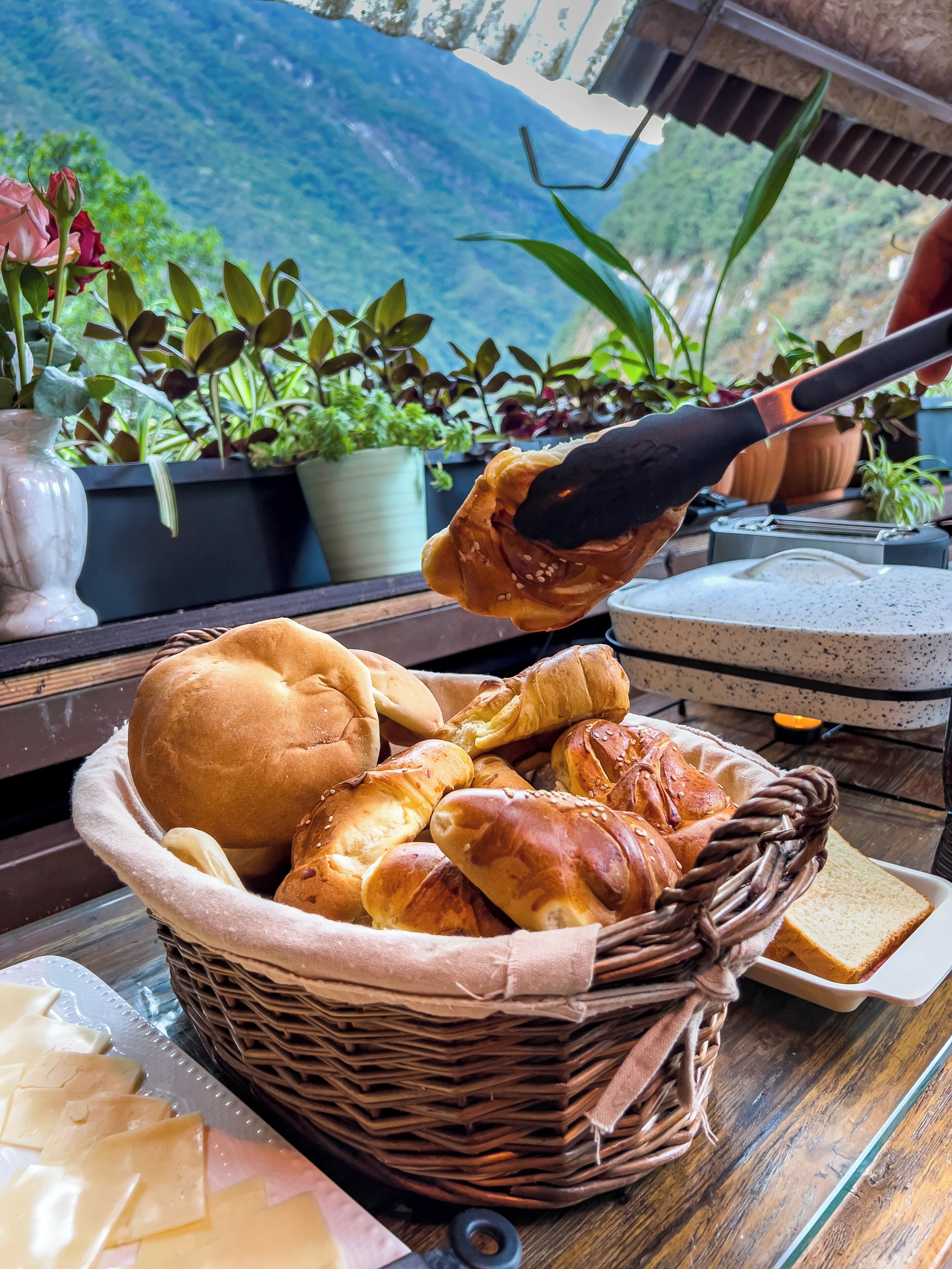 A basket of bread on a table with a mountain view in the background.