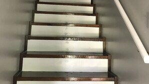 Un escalier avec des marches en bois et une rampe blanche, menant à une porte blanche située en haut.