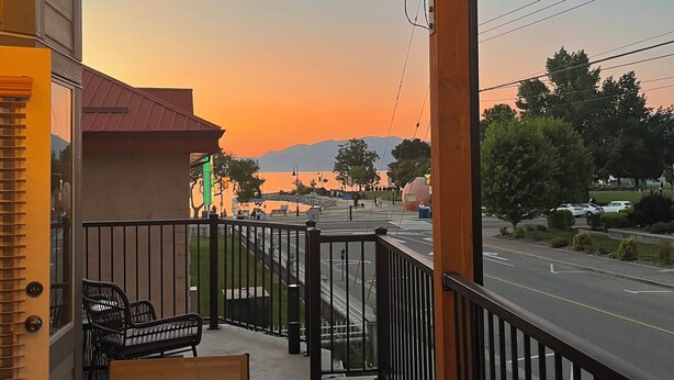 Une terrasse de restaurant avec des places assises en plein air, une vue sur le coucher de soleil et une rue en arrière-plan.