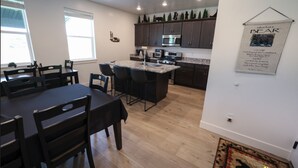 Une cuisine moderne avec des meubles de couleur sombre, un îlot central et un coin repas comprenant une table et des chaises.