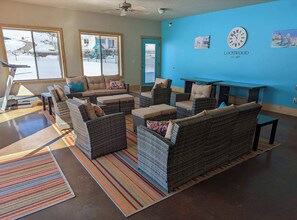 A lounge area with wicker furniture, a blue wall, and a clock.