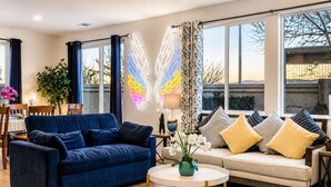 A living room with a blue sofa, a round coffee table, and a beige sofa with patterned cushions.