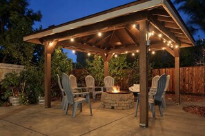 A covered outdoor seating area with chairs and a central fire feature. - Family & Group Retreat Near Monterey · Sleeps 16–20 · Sauna · Putting Green (Salinas)