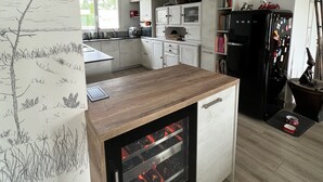 Une cuisine moderne dotée d’une cave à vin intégrée, de meubles blancs et d’un plan de travail en bois.