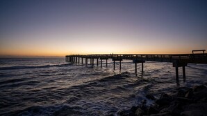 Une jetée qui s’avance dans l’océan au coucher du soleil.