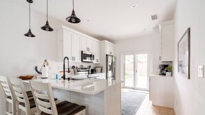 Une cuisine moderne avec des meubles blancs, un îlot central et des luminaires suspendus.