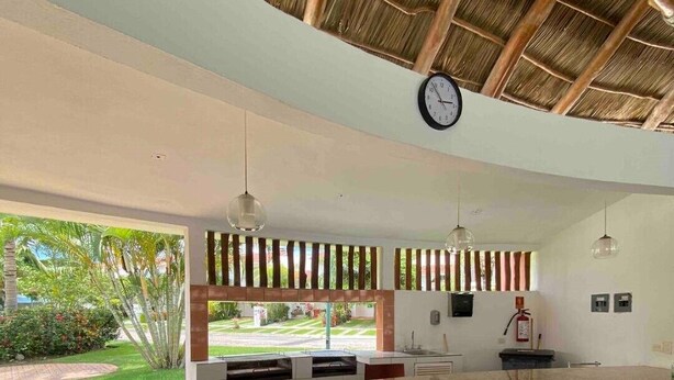 Moderni keittiö, jossa on graniittitaso, seinäkello ja näkymä puutarhaan.
