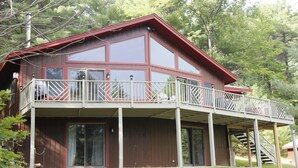 A two-story house with a balcony and a staircase leading to the upper floor. - Luxury Mnt. View Cabin with game room, hot tub, fire pit and private ski trails (Au Sable Forks)