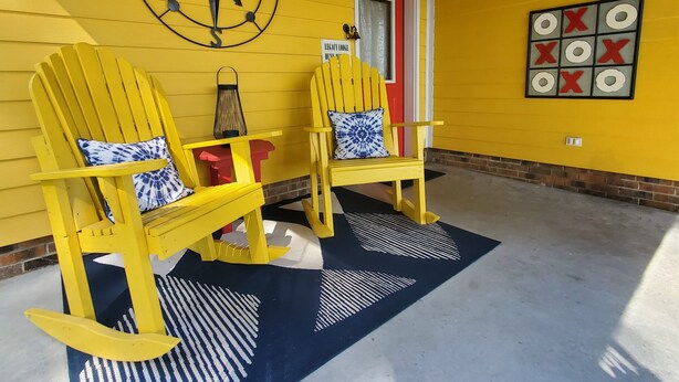 A yellow porch with two Adirondack chairs, a compass wall decoration, a red door, and a tic-tac-toe board. - A remote getaway ... Enjoy nature, have fun and embrace relaxation! (windsor)