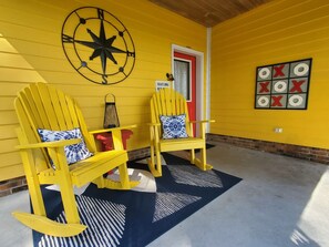 A yellow porch with two Adirondack chairs, a compass wall decoration, a red door, and a tic-tac-toe board. - A remote getaway ... Enjoy nature, have fun and embrace relaxation! (windsor)