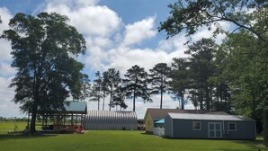 A grassy area with a small building, a covered structure, and several trees. - A remote getaway ... Enjoy nature, have fun and embrace relaxation! (windsor)