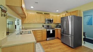 Cocina con armarios de madera, electrodomésticos de acero inoxidable y encimera de granito.