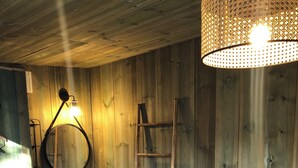 Een houten kamer met een bed, een ladder, een ronde spiegel en een plank met een mand.